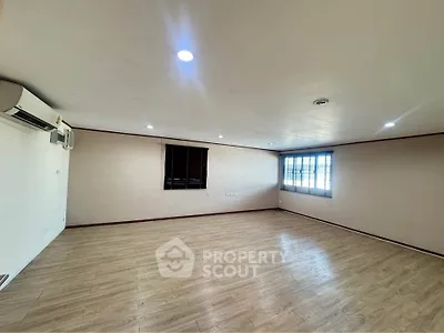 Spacious empty room with wooden flooring and air conditioning, ideal for customization.