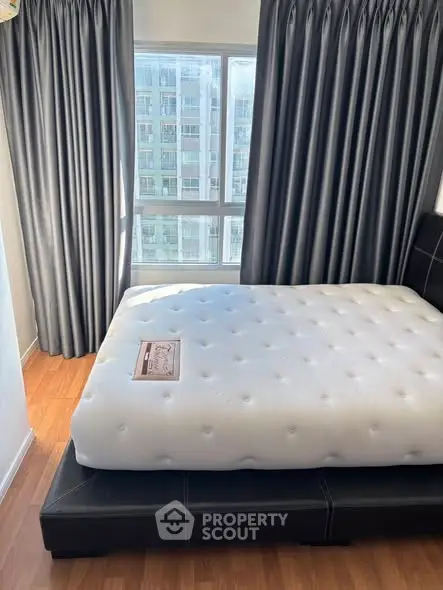 Modern bedroom with large window and stylish curtains in urban apartment.