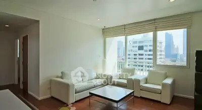 Spacious living room with modern white sofas and large windows offering city views.