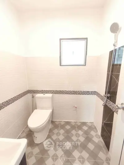 Modern bathroom with sleek tiles and compact design, featuring a window for natural light.