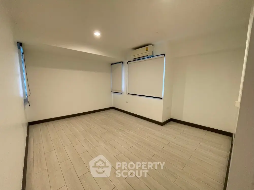 Spacious empty room with air conditioning and wooden flooring, perfect for customization.