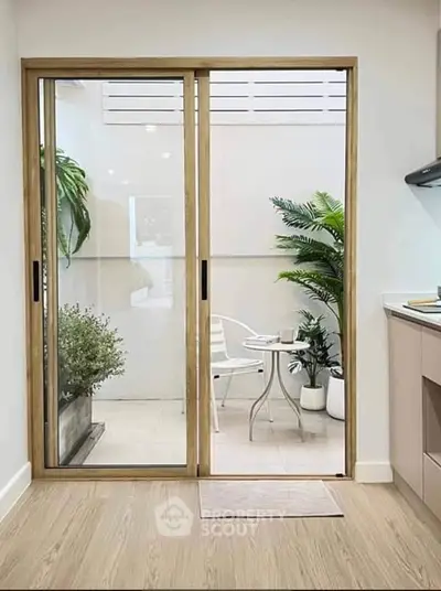 Chic kitchen with sliding glass doors opening to a cozy patio with lush greenery.