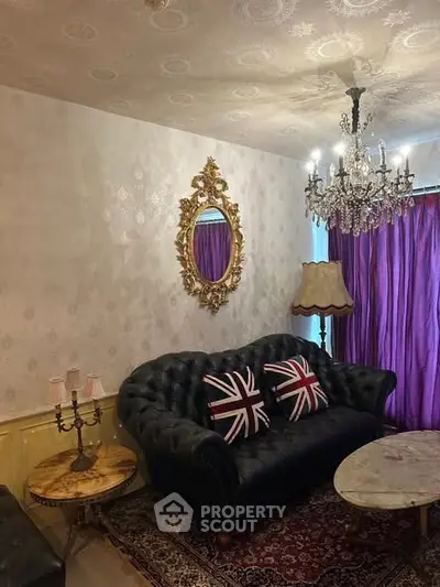 Elegant living room with vintage decor, featuring a luxurious sofa, ornate mirror, and chandelier lighting.