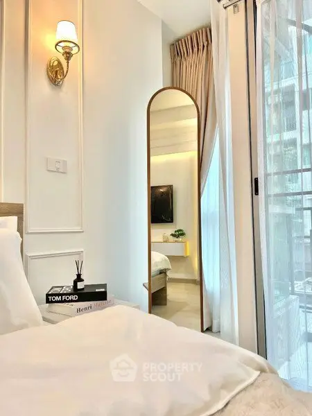 Elegant bedroom with modern decor, featuring a stylish mirror and soft lighting for a cozy ambiance.