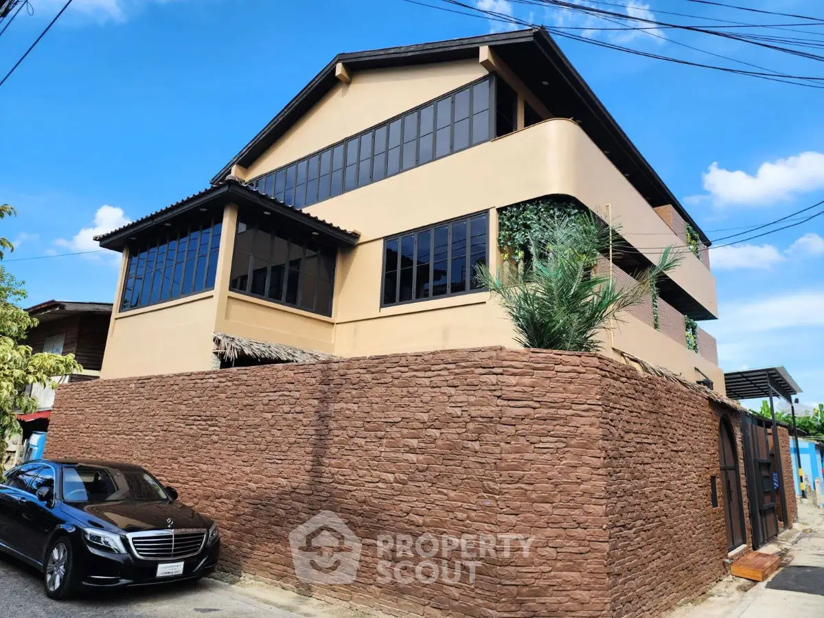 Stunning modern house with stone wall and luxury car parked outside, showcasing elegant architecture.