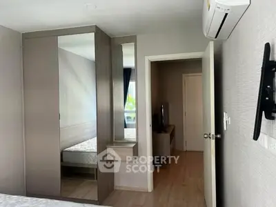 Modern bedroom with sleek wardrobe and wall-mounted TV in a stylish apartment.
