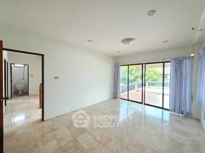 Spacious living room with marble flooring and large sliding glass doors leading to a balcony with a view.