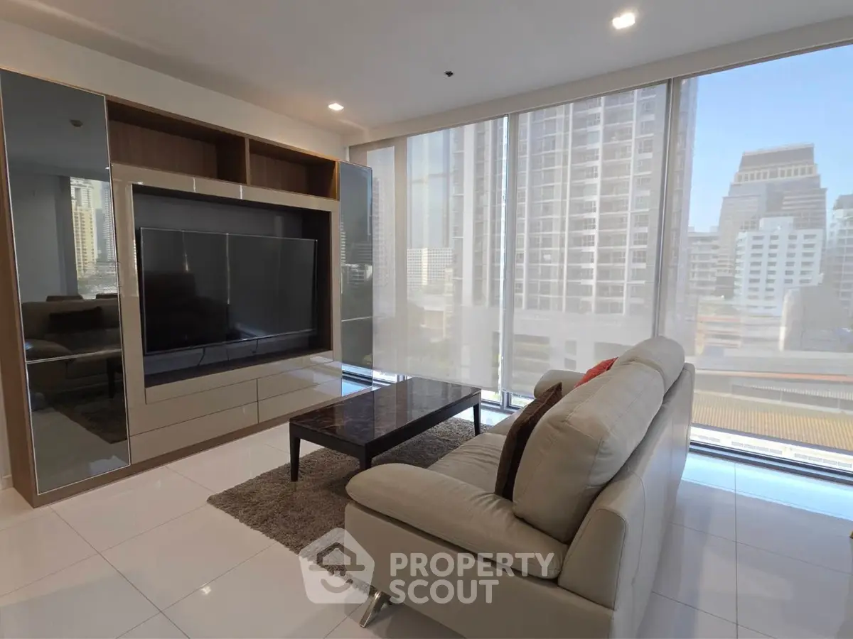 Modern living room with sleek furniture and city view through large windows.