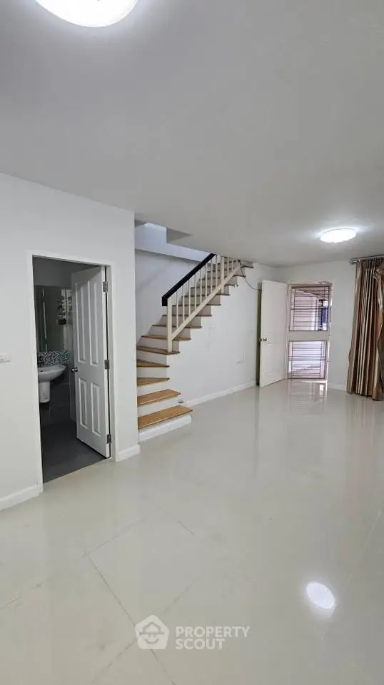 Spacious modern interior with staircase and glossy tiled flooring in a bright open-plan layout.