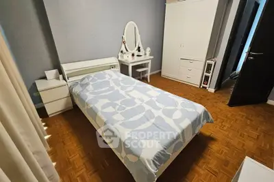 Cozy bedroom with stylish decor and parquet flooring, featuring a single bed and elegant vanity.