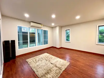 Spacious living room with wooden floors and large windows, perfect for natural light.