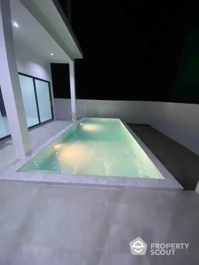 Modern luxury home with sleek private pool and elegant night lighting.