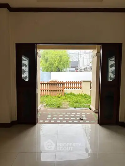 Spacious living room with open doors leading to a lush garden view, perfect for relaxation.