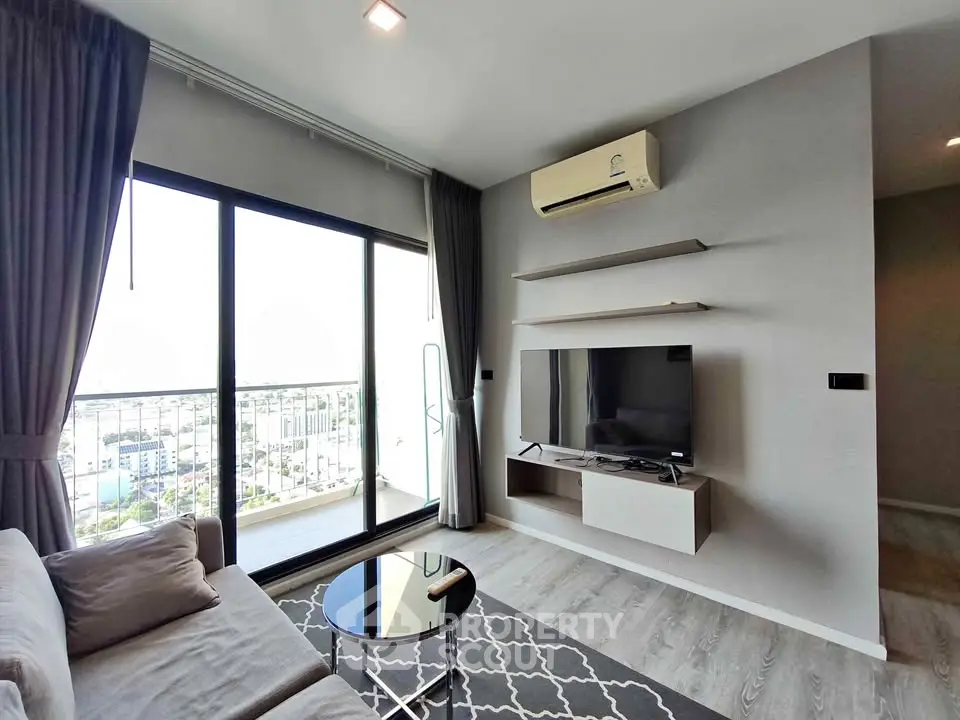 Modern living room with balcony view, featuring sleek furniture and air conditioning.