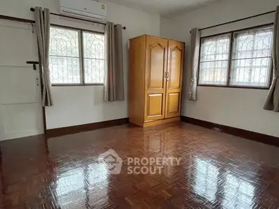 Spacious empty room with polished wooden floors and large windows