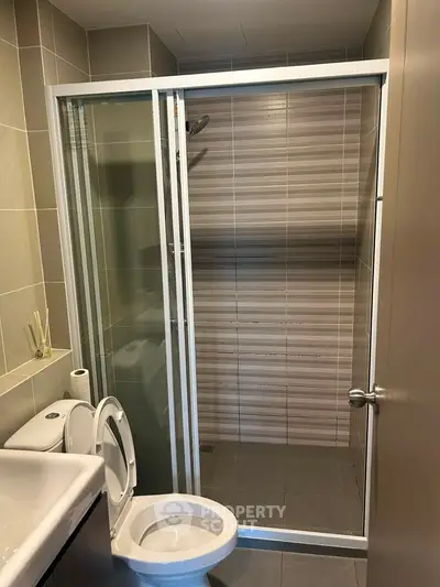 Modern bathroom with glass shower enclosure and sleek fixtures in a contemporary apartment.