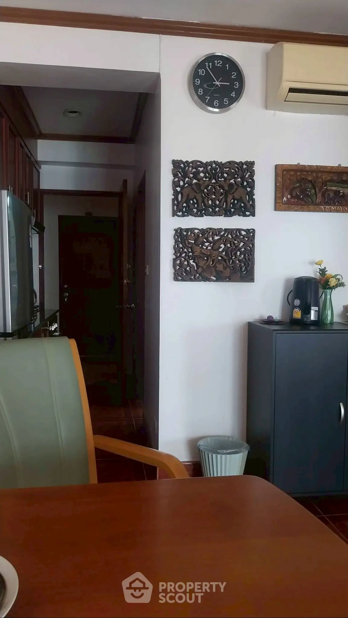 Cozy interior with wooden accents and wall art, featuring a clock and air conditioning unit.