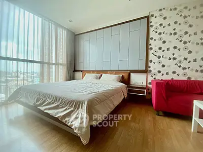 Spacious bedroom with large windows and modern decor in a high-rise apartment.