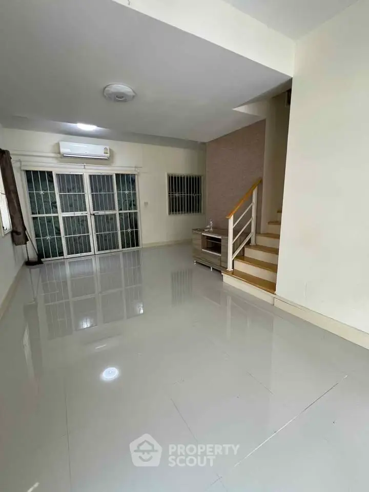 Spacious living room with glossy tiled floors and staircase in modern home