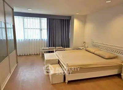 Spacious bedroom with elegant decor and large window for natural light.