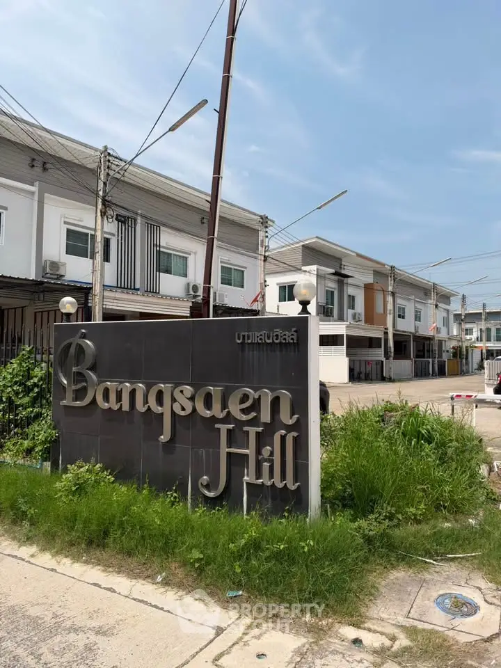 Modern townhouse complex with Bangsaen Hill sign and clear blue sky.