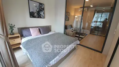 Modern bedroom with stylish decor and glass partition leading to living area.