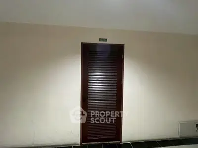Dimly lit corridor with a closed wooden door, ideal for secure storage or utility access.