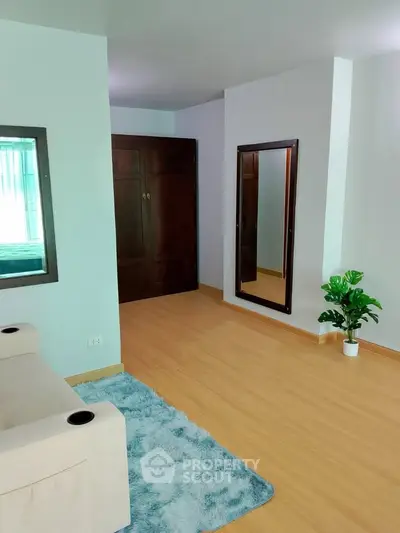 Spacious living room with wooden flooring and large mirror, perfect for modern living.