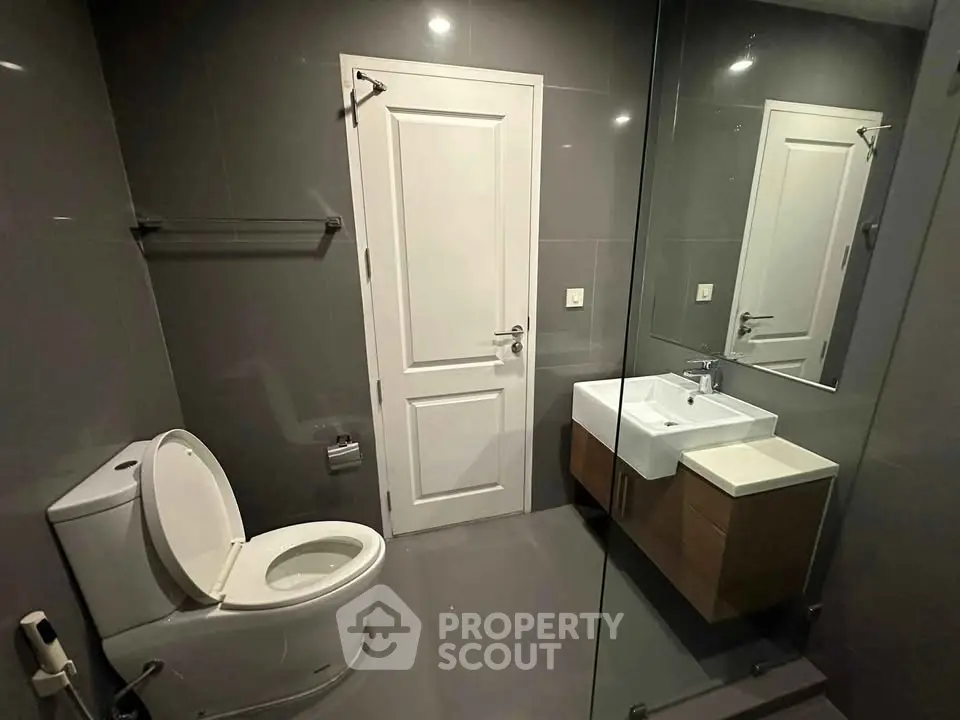 Modern bathroom with sleek design featuring a wall-mounted sink and glass shower enclosure.