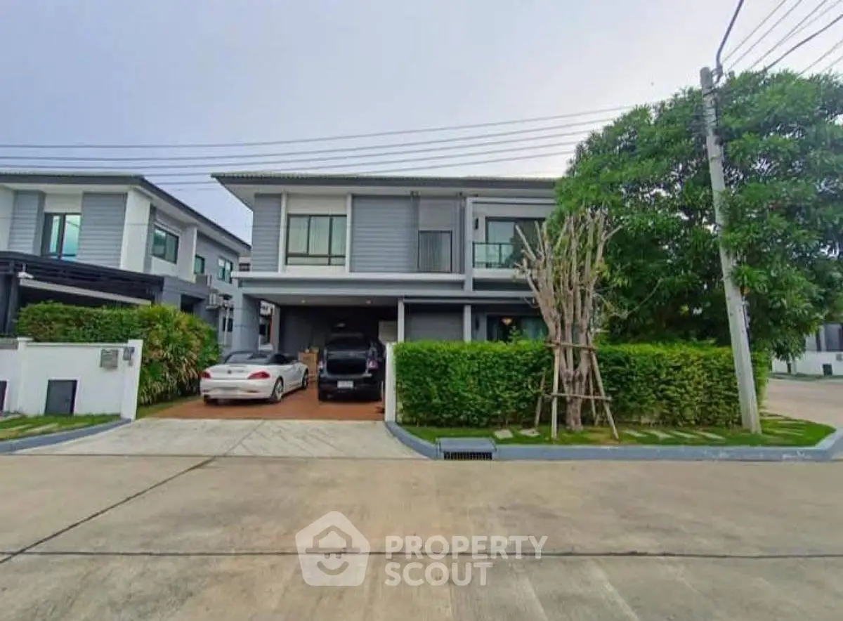 Modern two-story house with driveway and lush greenery in a suburban neighborhood.