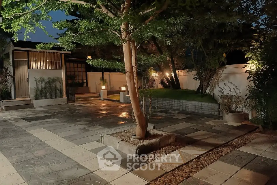 Serene garden with ambient lighting and paved pathways for tranquil outdoor living.