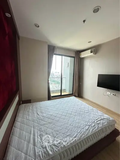 Modern bedroom with large window and city view, featuring a wall-mounted TV and air conditioning.