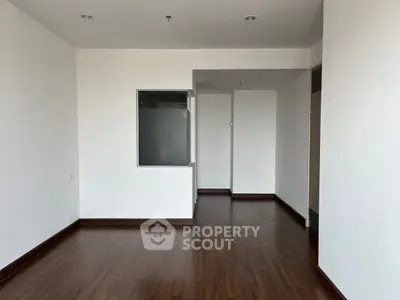 Spacious empty room with wooden flooring and white walls, ideal for customization.