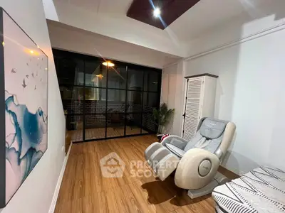 Modern living room with massage chair and stylish decor, featuring wooden flooring and glass sliding doors.