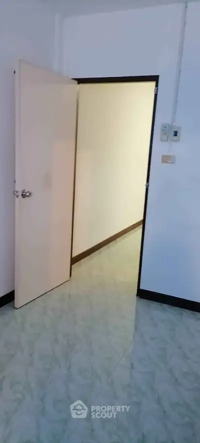 Spacious interior hallway with open door and tiled flooring in a modern apartment.