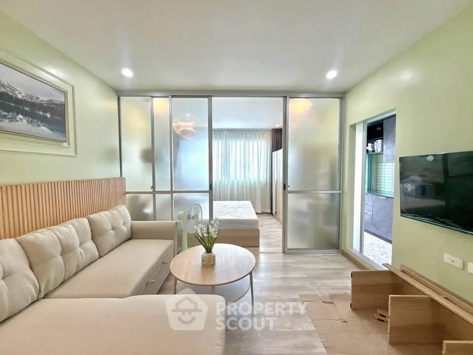 Modern living room with cozy sofa, stylish decor, and sliding glass doors leading to a bright bedroom.