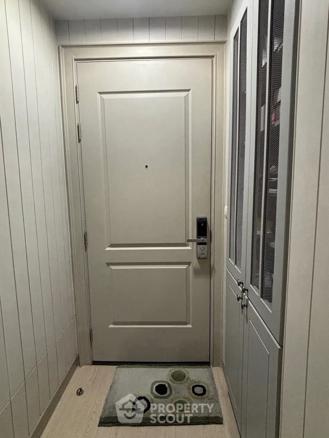 Modern apartment entrance with secure door and stylish mat