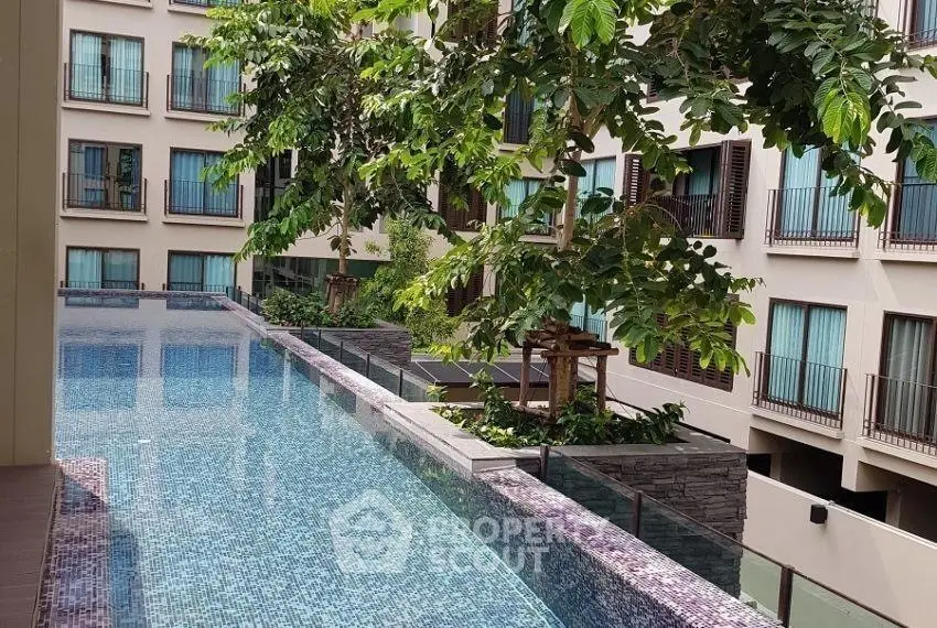 Luxurious apartment complex with stunning infinity pool and lush greenery.