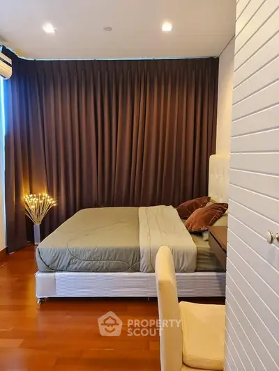 Cozy bedroom with elegant drapes and modern lighting, perfect for relaxation.