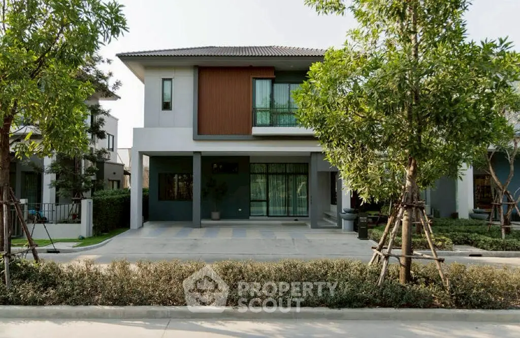 Modern two-story house with sleek design and landscaped front yard in a suburban neighborhood.