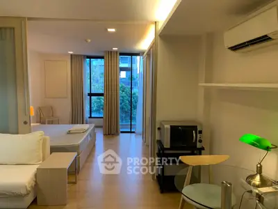 Modern studio apartment with open layout, featuring a cozy living area, bed, and kitchenette with natural light.