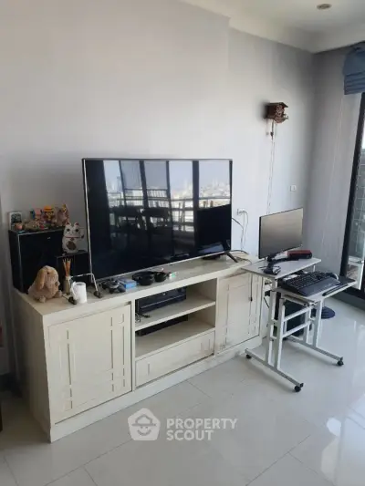 Modern living room with large TV and city view, featuring sleek furniture and bright natural light.