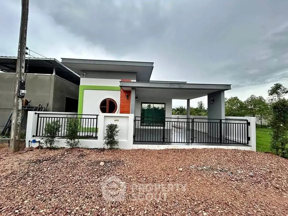 Modern single-story house with unique circular window and spacious front yard.