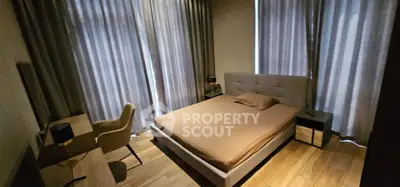 Cozy bedroom with modern furnishings and natural light through large windows.