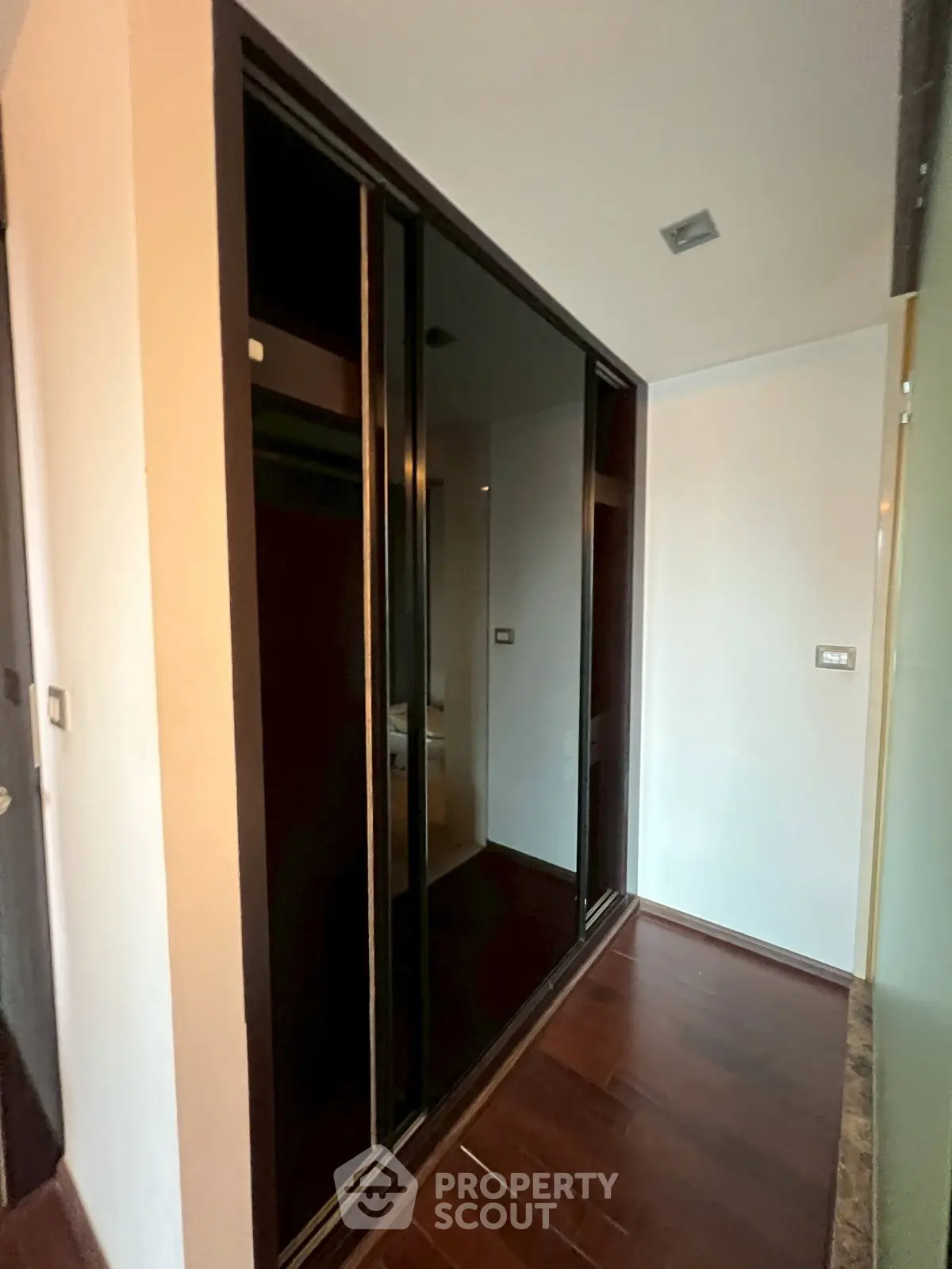 Modern hallway with sleek dark sliding closet doors and wooden flooring