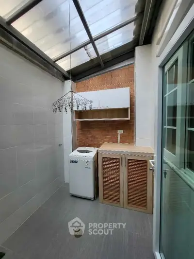 Charming laundry area with washing machine and rustic brick wall under skylight.