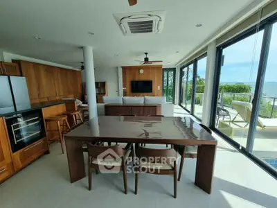Luxurious open-plan living room with ocean view, modern furniture, and expansive glass doors leading to a balcony.