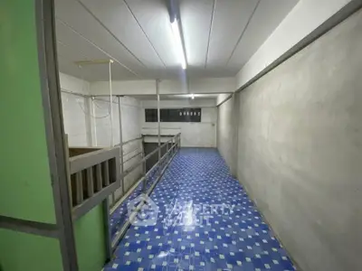 Spacious industrial-style room with blue tiled flooring and fluorescent lighting.