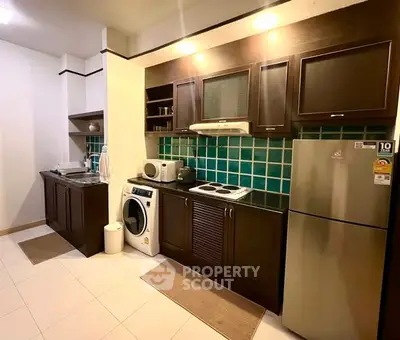 Modern kitchen with dark wood cabinets, washing machine, and stainless steel fridge in a cozy apartment.