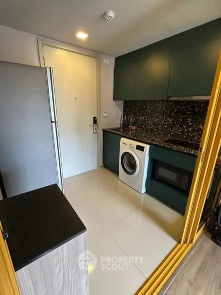 Modern kitchen with sleek cabinets, washing machine, and microwave in compact space.
